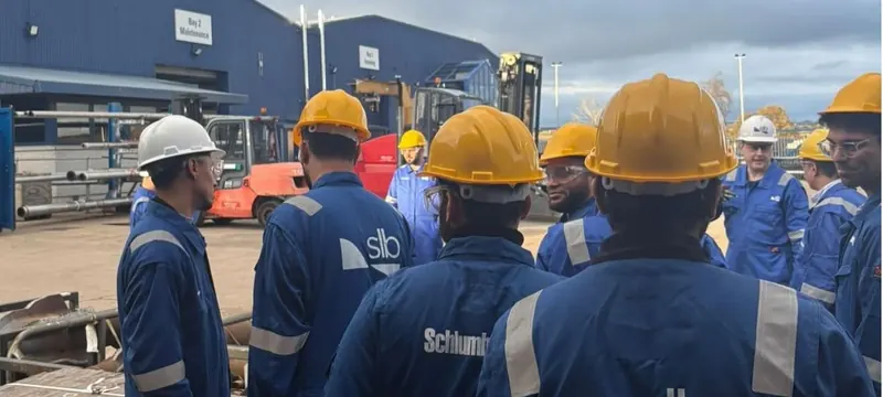 Chapter members in branded coveralls and hard hats on a site visit to an SLB facility.